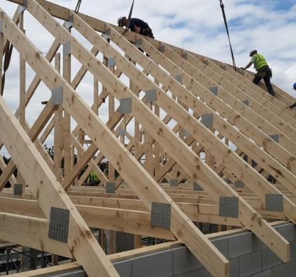 Wooden roof trusses installed on gable roof construction site showing triangular framework and metal connector plates