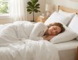 Person sleeping comfortably on a thin cooling pillow with breathable white bedding in a bright bedroom